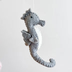 Gray plush seahorse toy on a white background