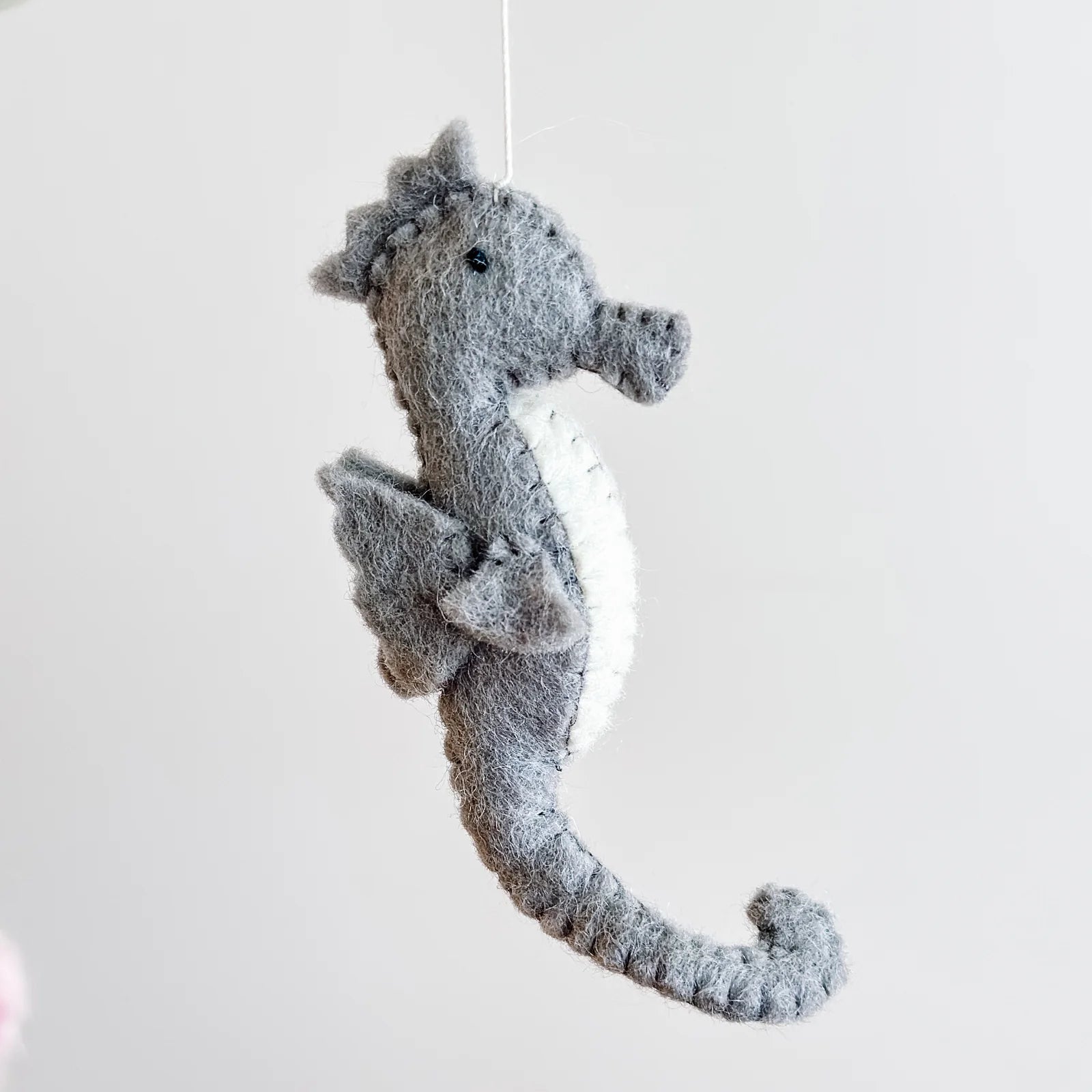 Gray plush seahorse toy on a white background