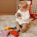 toddler holding fabric shapes beanies sensory toy neutral colours