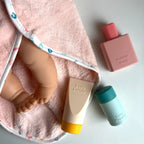 a close up of the tiny harlow bath accessory pack that comes with a bag, body lotion,baby doll towel, baby powder and bubble bath all for pretend play with dolls called tiny bath time