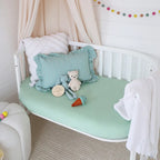 Snuggle Hunny mint organic fitted cot sheet on a nursery cot styled with soft bedding and toys, breathable stretch cotton jersey baby sheet