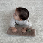 baby using tummy time log pillow for support during tummy time