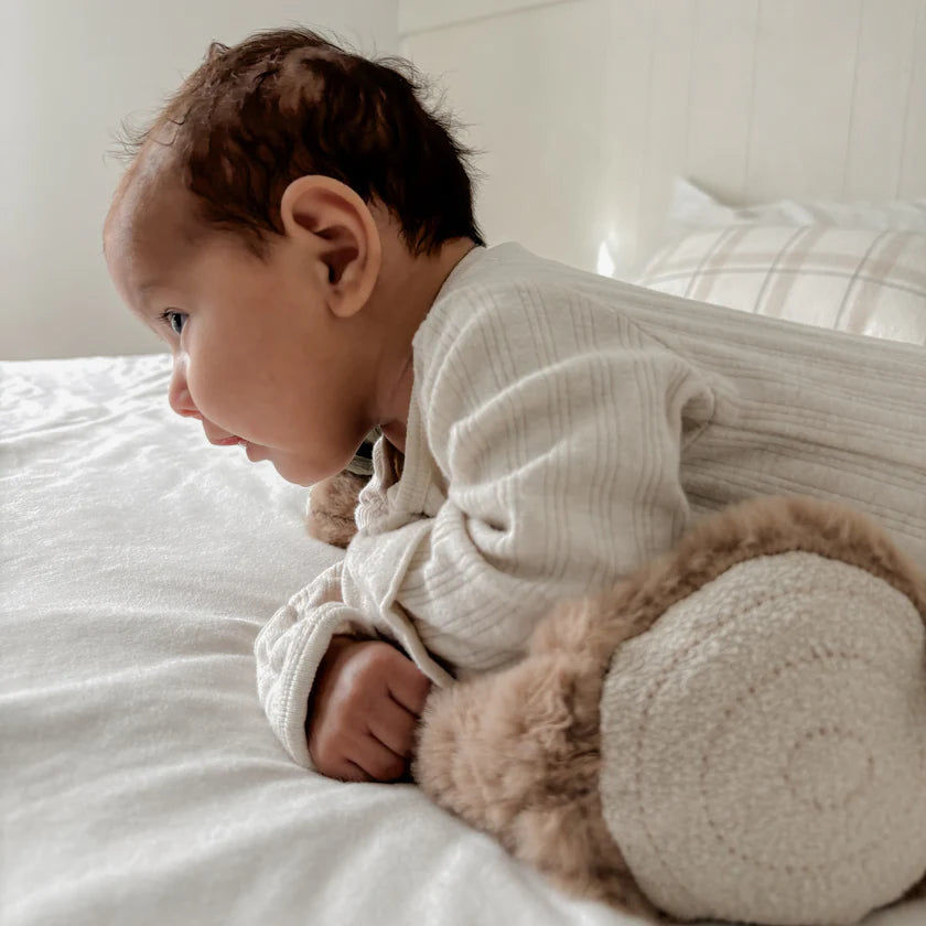 baby practising tummy time with supportive log shaped pillow