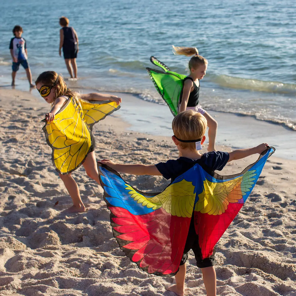 Children playing on a beach with colorful dress up wings