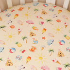 Close up of Beach Fun print organic cotton cot sheet featuring playful beach and summer themed illustrations