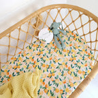 Sunny Citrus organic bassinet sheet fitted on a woven bassinet with yellow bedding in a fresh citrus themed nursery