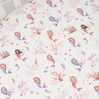 Mermaid print organic fitted cot sheet laid flat showing playful mermaids and sea themed illustrations on soft cotton jersey fabric