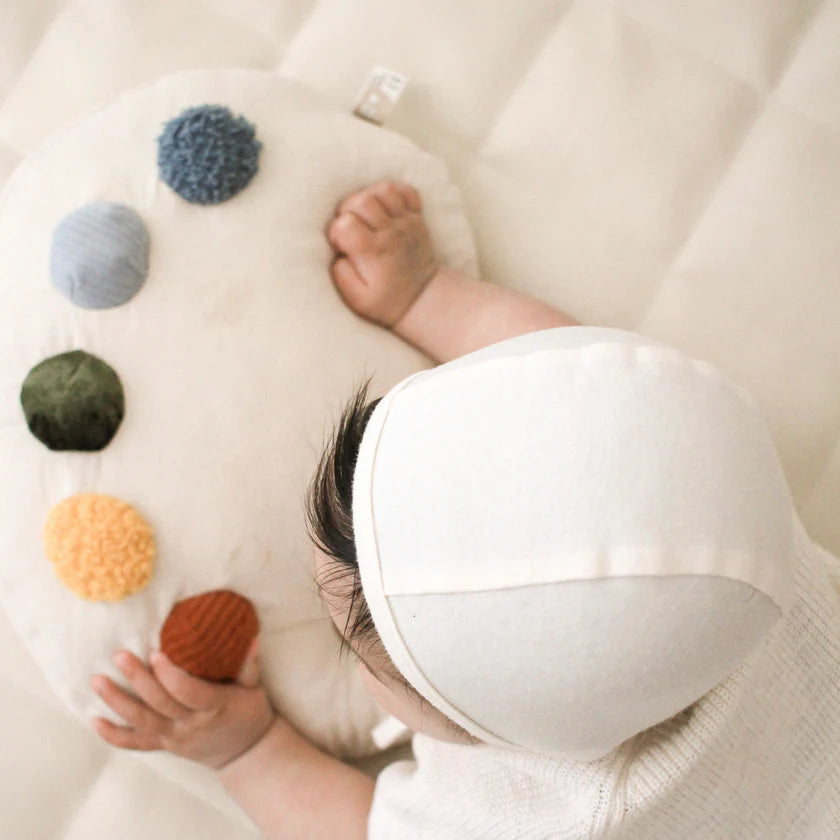baby lying on Little Lamb Kind tummy time paint palette pillow during tummy time