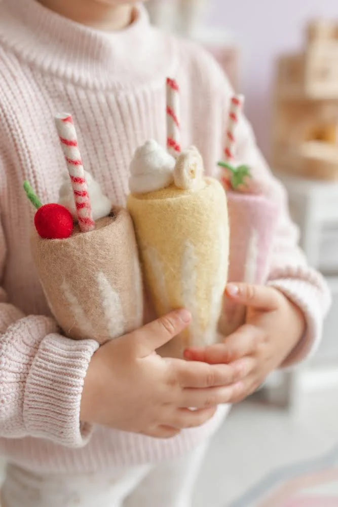 child holding felt strawberry, chocolate and banana milkshake toy handmade wool pretend play drink diner Juni Moon