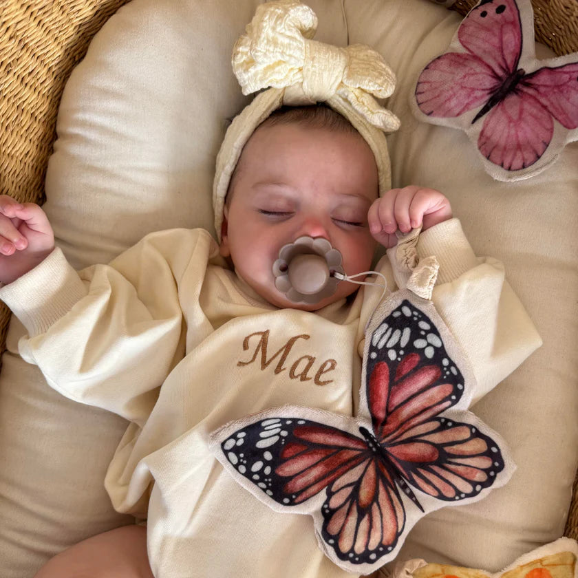 baby holding soft butterfly toy with crinkle and rattle features
