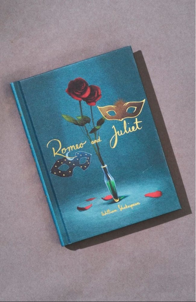 Romeo and Juliet collector’s edition hardcover book by William Shakespeare with blue cover, gold foil title, rose illustration and decorative mask